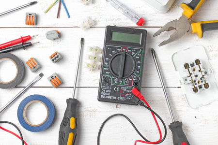 Flat lay, appliances and electrician tools on a rustic white background, close-up.