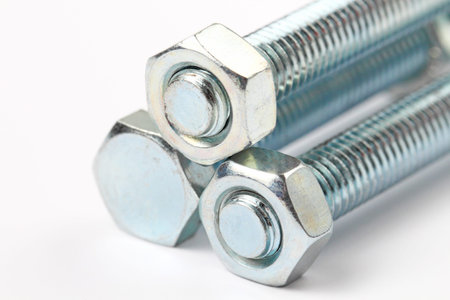 Three bolts with nuts on a white background close-up.