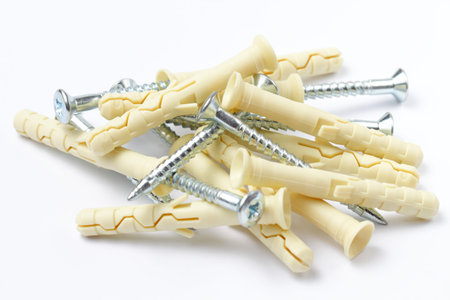A scattering of dowels with screws on a white background, close-up.