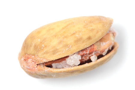 Pistachio nut with grains of salt closeup on a white background.