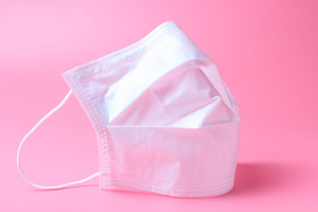 Medical mask close-up on a pink background, the concept of the fight against coronovirus and other...