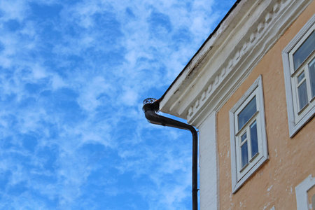 Corner of a stone old house on a background of bright blue sky.