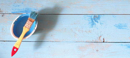 Brush with paint on a rustic background, blue color, close-up.