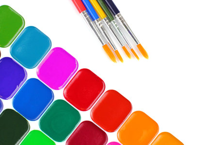 Bright color paints, brushes on a white background. School or education theme concept. Top view,...