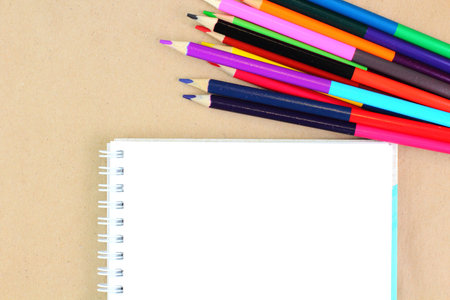 Colored pencils, sketchbook on a craft background. School or education theme concept. Top view, flat...