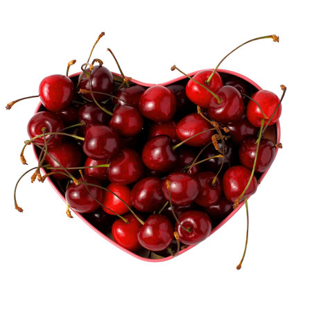 Ripe cherries in a container in the shape of a heart. Top view, place for text, copy space, white...