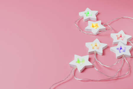Garland of stars with colored lights on a pink background, close-up, Christmas and New Year decorations.の写真素材