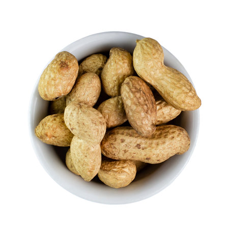 Peanuts in a shell in a white ceramic bowl on a white background, isolate. Top view, flat lay.