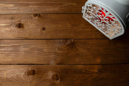 Lantern with a burning candle on a wooden background. Blank for festive decoration. Copy space, top view, flat lay.の写真素材