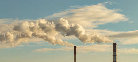 industrial chimneys on a background of a cloudy sky, a long plume of smoke from chimneys, the concept of protecting nature or earth day.の写真素材
