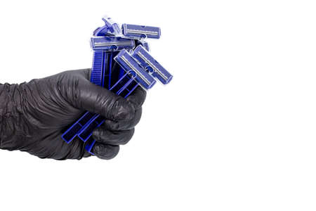 A bunch of razors in the hand of a man in a black glove, a concept for a banner or flyer for fathers day, a simple gift for a man, copy space.の写真素材