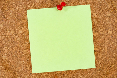 A piece of paper for notes or memos pinned with a pushpin on a cork wall or office board, copy space.の写真素材