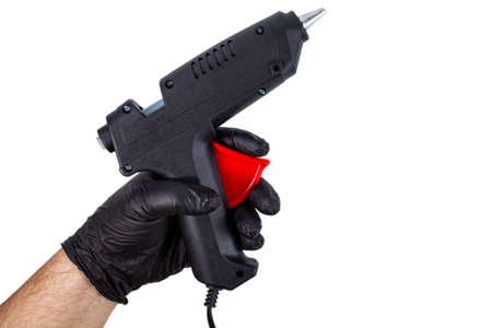 Thermal gun with glue in the hand of a man in a black glove on a white isolatedの写真素材