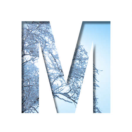 Winter letters. The letter M cut out of paper on the background of the winter sky and snow-covered tree branches on a frosty winter sunny day. Decorative nature alphabet, font collection.の写真素材
