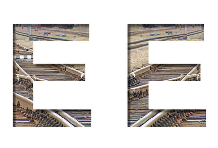 Railway font. The letter E is cut out of white paper against the background of railroad rails,...