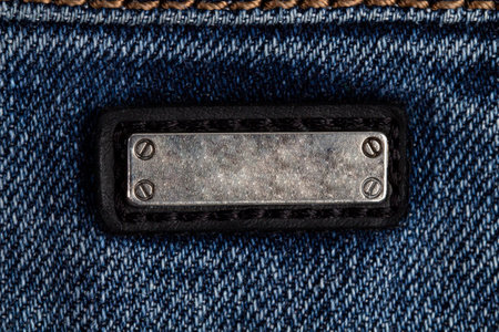 A metal plate with screws as a label on a jeans pocket close-up, copy space.の写真素材