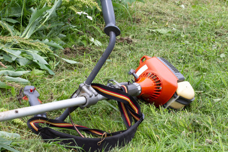 Garden trimer with a gasoline engine on the background of summer grass.