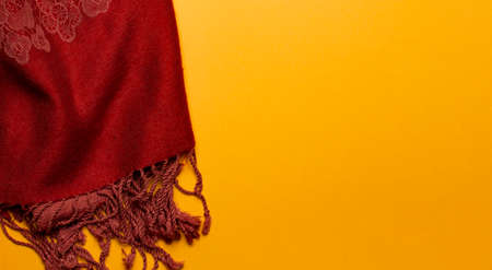 Bright warm scarf on a yellow background, top view, place for text, banner mockup with autumn mood, copy space.の写真素材
