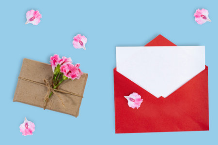Congratulatory envelope with a sheet for text and a gift on a blue background, top view.