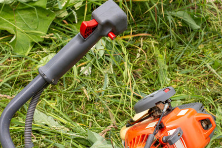 Garden trimer on green mowed grass, control handle and petrol engine