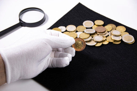 Mans hand in a white glove holds a coin, coins collecting concept.