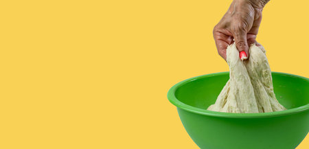 Dough in woman hand on yellow, concept of fresh baking, space for text.