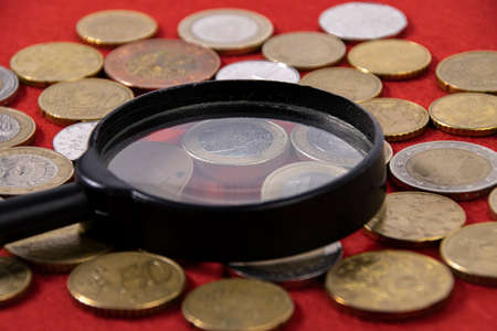 Collection of coins and collector magnifying glass on redの写真素材