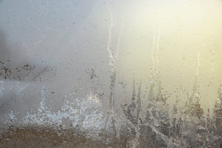 Iced glass against the background of a blurred dawn sun as a background, close-up