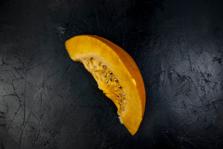 Quarter of a pumpkin on a black stone table, top viewの写真素材