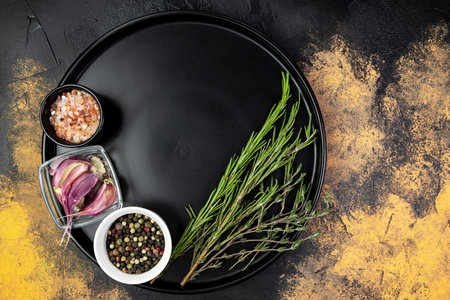 Black plate with condiments and aromatic herbs on a cutting table, top view, flat lay, copy space, mockup for menuの写真素材