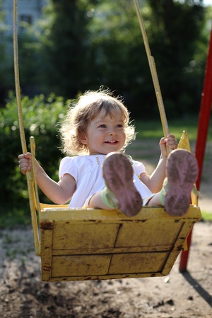 Playing on the swings after summer rain - shallow depth of field, back lighting  の写真素材