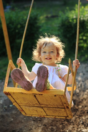 Cute little girl playing on the swingsの写真素材