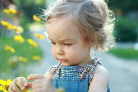Cute child explorer flowers in garden – shallow depth of field