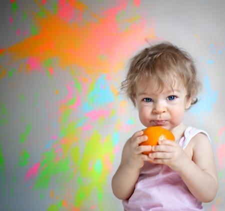 Angry baby with orange against grunge painted backgroundの写真素材