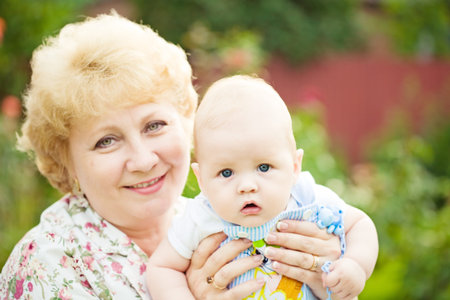 Happy grandmother holding baby boy outdoors