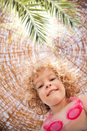 Low angle view of happy smiling child on summer vacations by the seaの写真素材