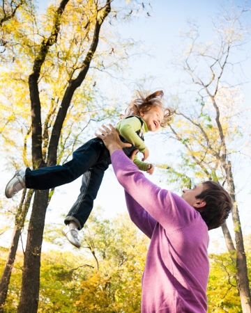 Man with child having fun in autumn park  Focus on manの写真素材