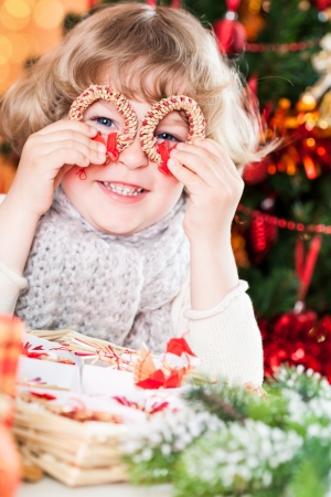 Funny smiling child holding handmade eco decorations against Christmas lightsの写真素材