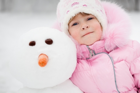 Happy child with snowman in winterの写真素材