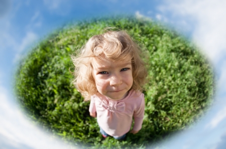 Funny child standing on green grass against blue sky  Fisheye shootの写真素材