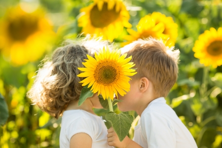 Happy children with sunflower playing in spring fieldの写真素材