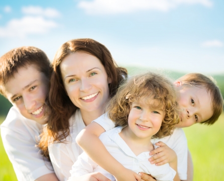 Happy family having fun outdoors in spring green field against blue sky backgroundの写真素材