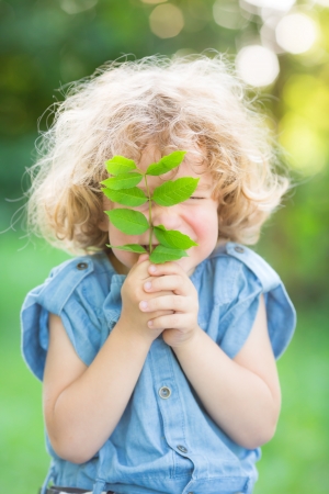 Child holding young plant against spring green background  Ecology conceptの写真素材