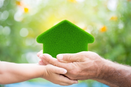 Family holding grass house in hands against green spring background  Environment protection concept