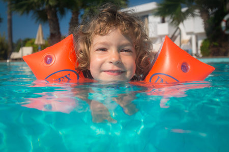 Happy child playing in swimming pool. Summer vacations concept