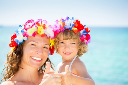 Happy family showing thumb up sign against blue sea backgroundの写真素材