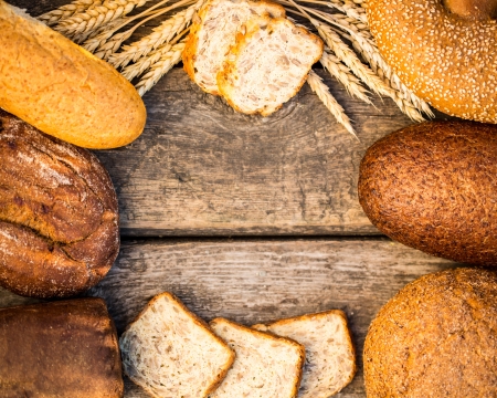 Homemade bread and wheat on the wooden table in autumn fieldの写真素材