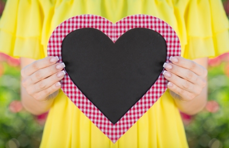 Woman holding heart blank in hands against green background. Spring family holiday concept. Mother`s dayの写真素材
