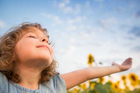 Happy child outdoors in spring sunflower fieldの写真素材