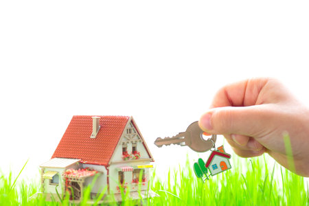 House on green grass and key in child`s hand. Real estate conceptの写真素材